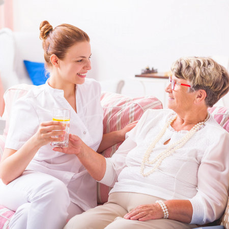 caregiver helping her old patient in drinking